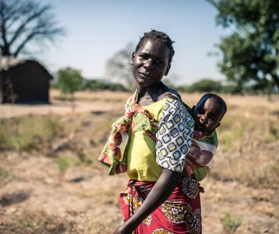 Malawi: Elube (32) stands with her baby in her small plot of farm land. Photo: Aurelie Marrier d'Unienville/Oxfam AUS