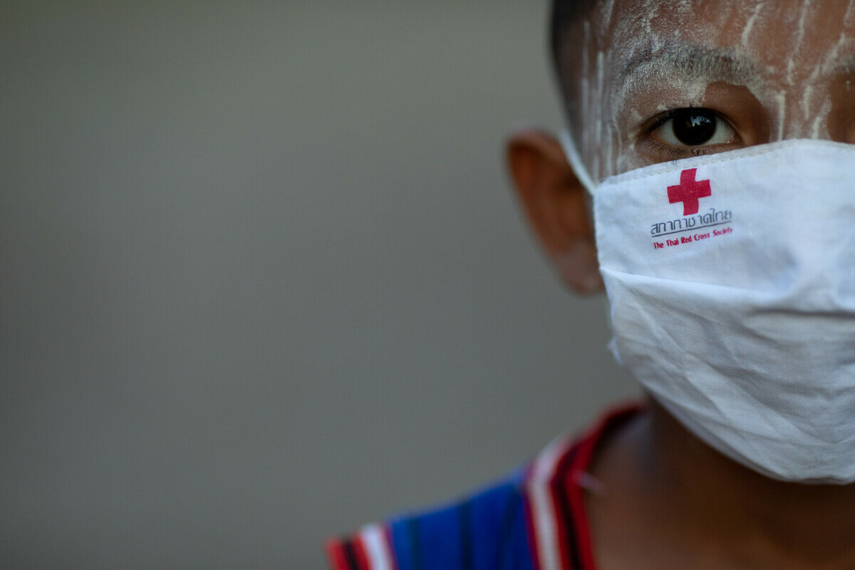 Thailand: An ethnic Mon boy from Myanmar wearing a face mask featuring the emblem of the Thai Red Cross Society in the community of the Talay Thai Market. Photo: Patipat Janthong / Oxfam Thailand: An ethnic Mon boy from Myanmar wearing a face mask featuring the emblem of the Thai Red Cross Society in the community of the Talay Thai Market. Photo: Patipat Janthong / Oxfam