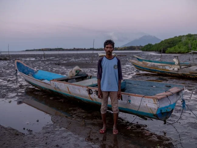 Mekko, Indonesia: Said (33) stands in front of his fishing boat. He now struggles to catch enough fish for his family's daily needs, due to climate change and the fish moving further and further out to sea. Oxfam acknowledges the support of the Australian Government through the Australian NGO Cooperation Program (ANCP). Photo: Vikram Sombu/Oxfam