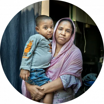 Bangladesh: Laily* with her son Safyun (2.5yr). Laily* works as a homebased garment worker. She joined garment factory at 12. Since 2019, she started working from home. Laily* brings orders from small factories and do them. Order like bed sheets, pillow covers, and one-piece dresses, these orders are given at home for sewing. With her income she hardly can earn 5000 taka. Photo: Fabeha Monir/Oxfam Bangladesh: Laily* with her son Safyun (2.5yr). Laily* works as a homebased garment worker. She joined garment factory at 12. Since 2019, she started working from home. Laily* brings orders from small factories and do them. Order like bed sheets, pillow covers, and one-piece dresses, these orders are given at home for sewing. With her income she hardly can earn 5000 taka. Photo: Fabeha Monir/Oxfam