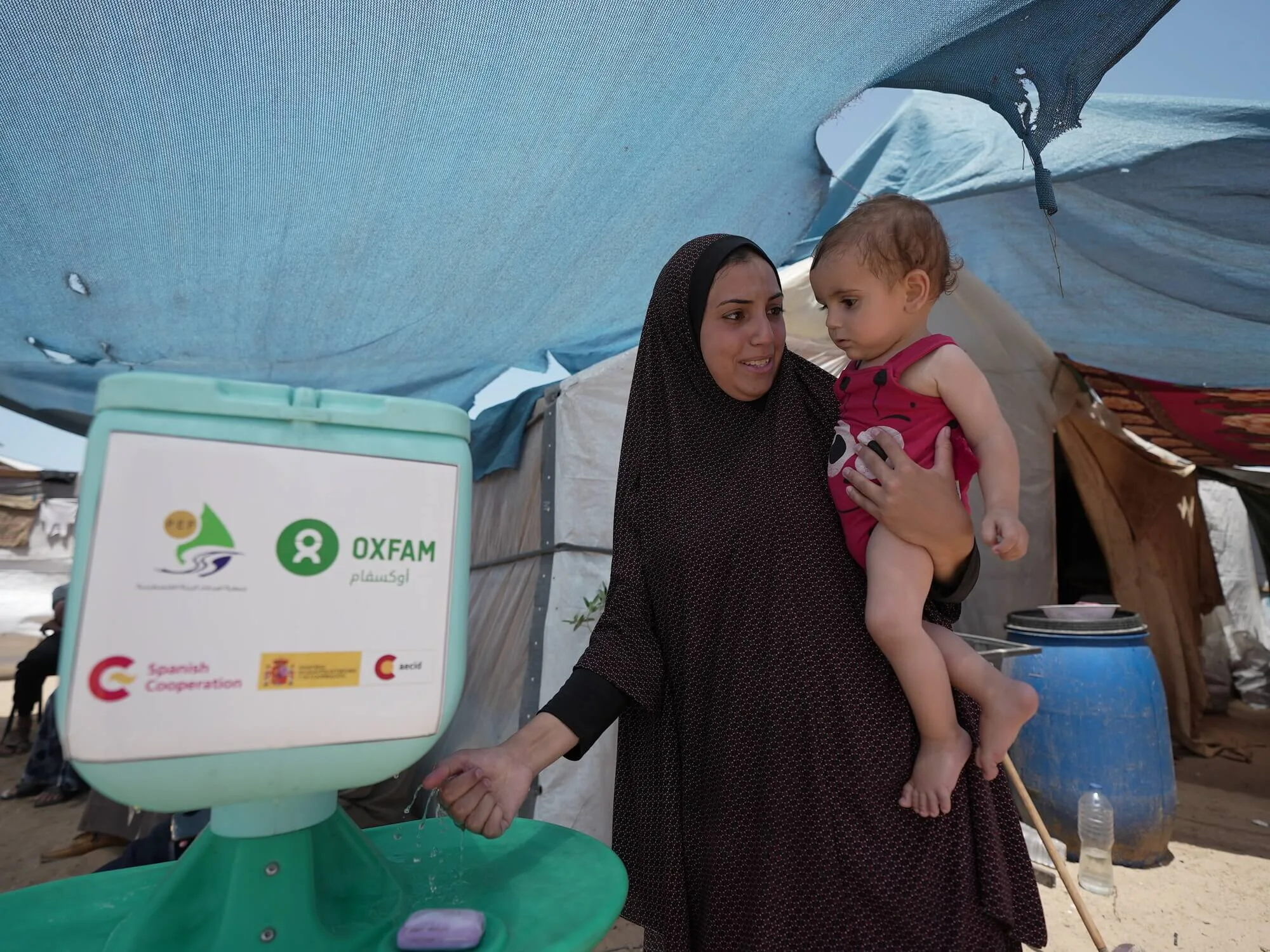 Palestinian Territory, Occupied: Duaa Abu Sabha uses the handwashing station that Oxfam distributed in response to people in the Al-Mawasi area in Khan Yunis Governorate. Photo: Alef Multimedia/Oxfam.