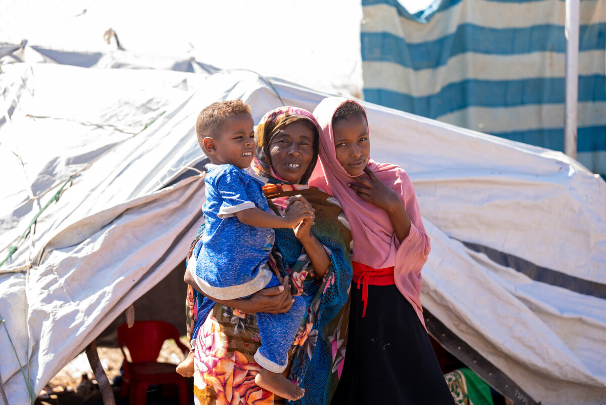 South Sudan: Asia Ahmed* stands with her mother, Suad, and her brother at their home in Renk, South Sudan. They are among nearly a million people displaced by the ongoing conflict in Sudan. Photo: Herison Philip Osfaldo/Oxfam