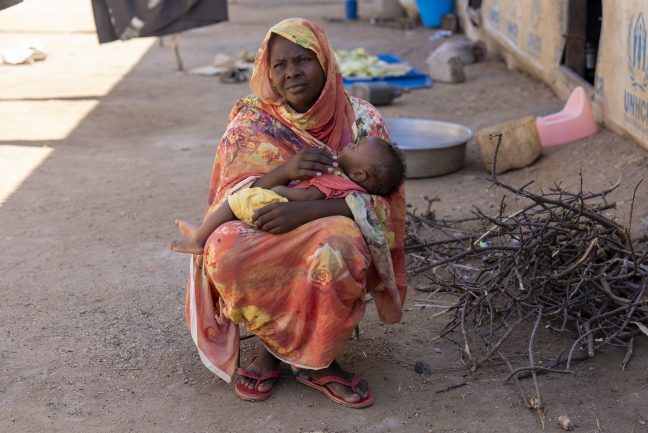 South Sudan: Shaima Ali, a refugee and mother of four who is among Oxfam cash assistant program participant sitted outside her home feeding her daughter Fahima in Renk, South Sudan. Photo: Herison Philip Osfaldo/Oxfam