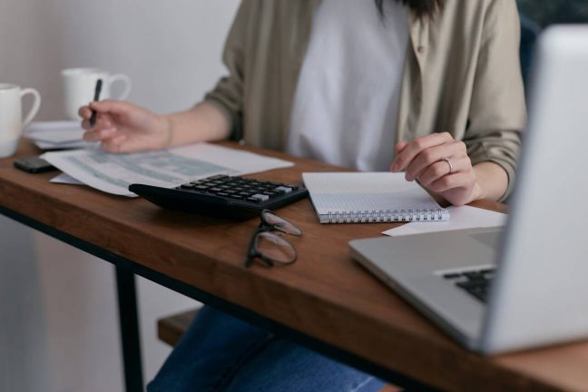 A person sitting in front of a calculator and computer. Photo: Mikhail Nilov/Pexels A person sitting in front of a calculator and computer. Photo: Mikhail Nilov/Pexels