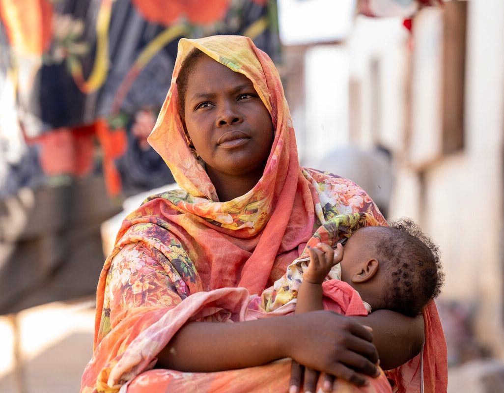 Renk, South Sudan: Shaima Ali, a refugee and mother of four who is participating in the Oxfam cash assistant program, sat outside her home feeding her daughter Fahima.