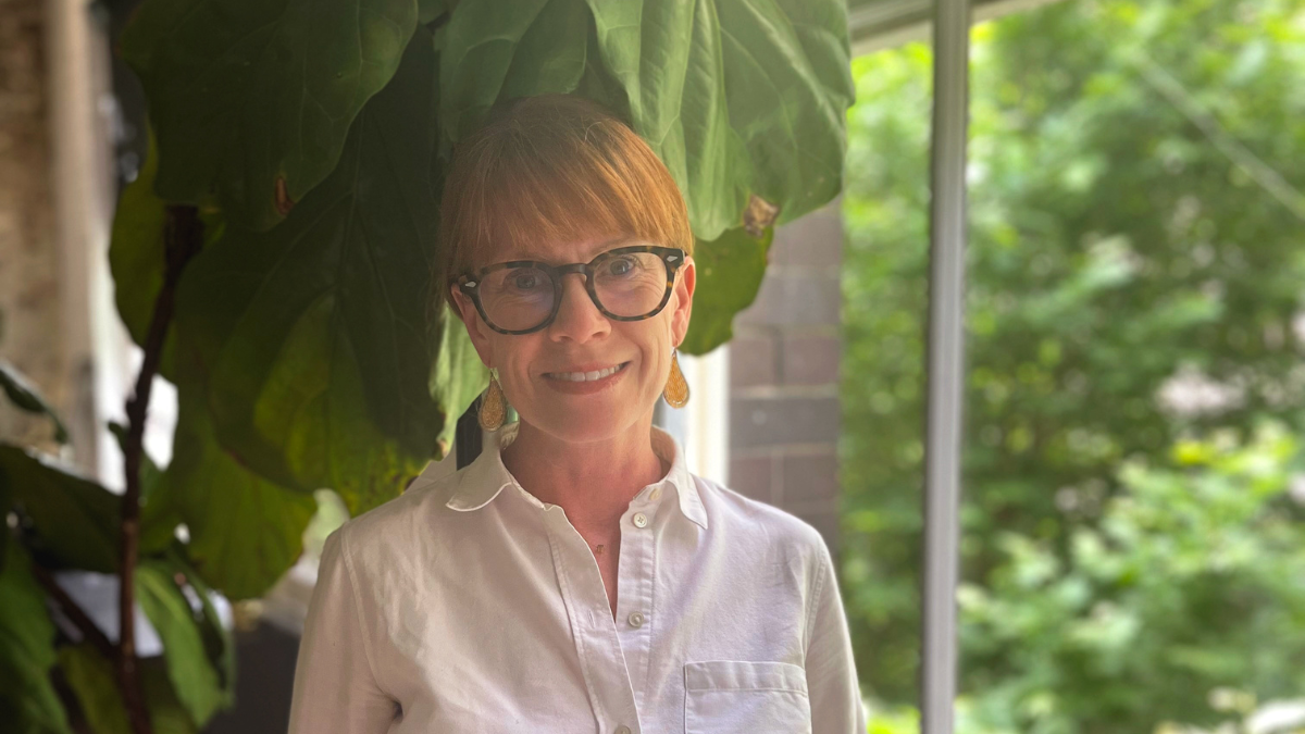 Australia: Jennifer Tierney stands in front of a window smiling. Photo: Oxfam