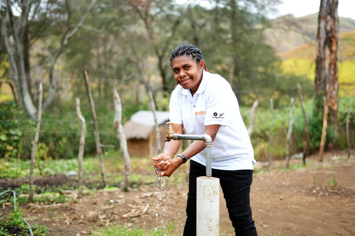 Papua ​New ​Guinea: Maigao Nigo, WASH Program Quality Officer, using a tap recently installed in the hamlet. Prior to the tap installation, the community had to walk hours every day to fetch water. Photo: Aimee Han/Oxfam